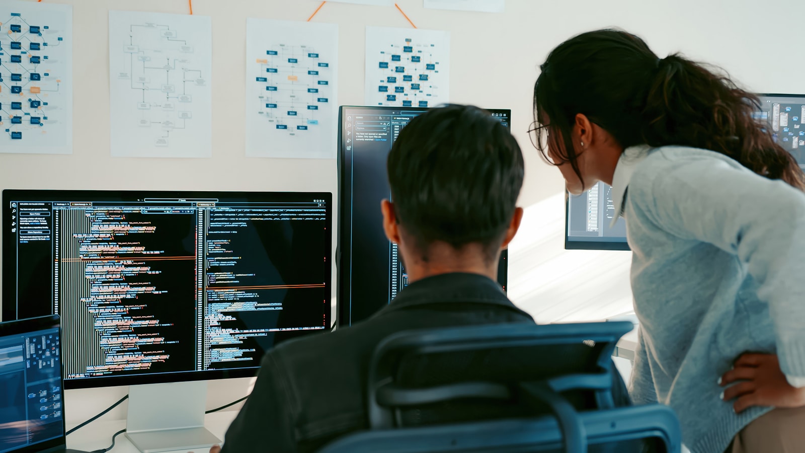 Photo showing software specialists working at a bank of computer monitors.