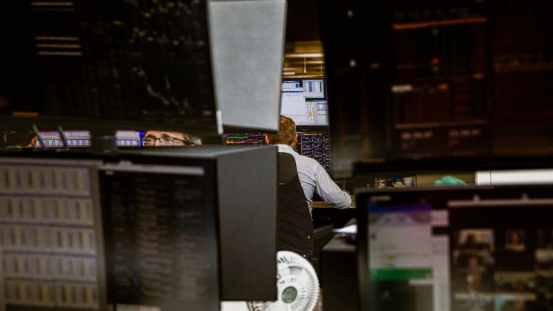 Photo of workers in finance industry surrounded by large computer screens
