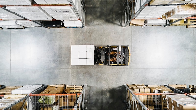 Photo of a warehouse worker moving a pallet of goods using a forklift