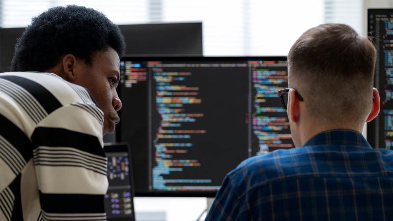 Photo of software coders in front of screens.