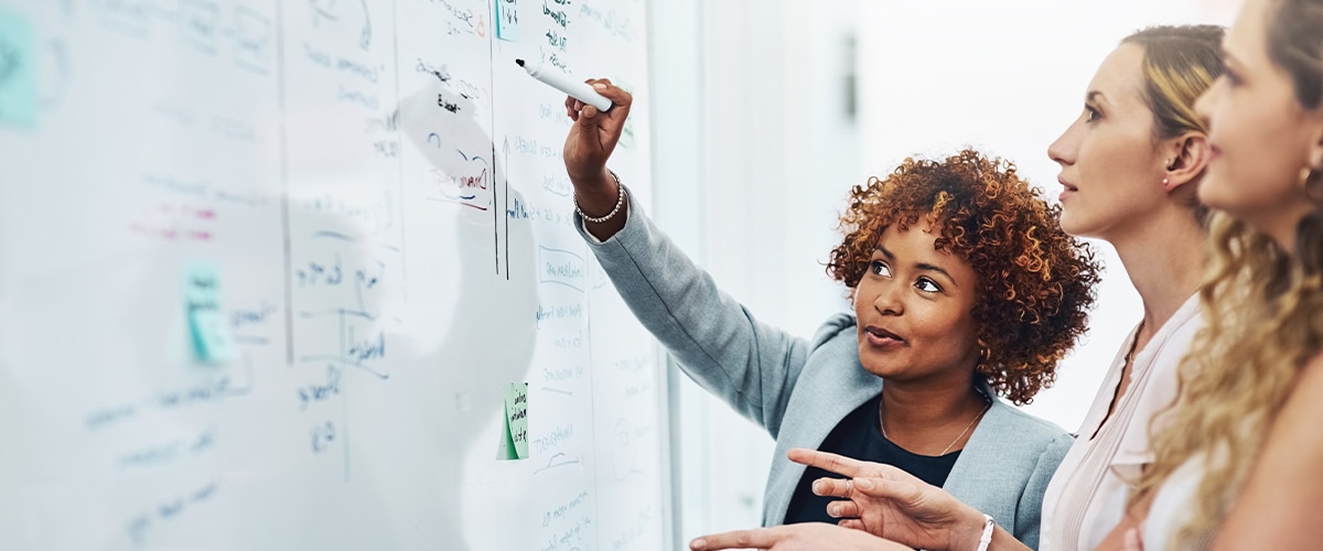 Three women standing at a whiteboard