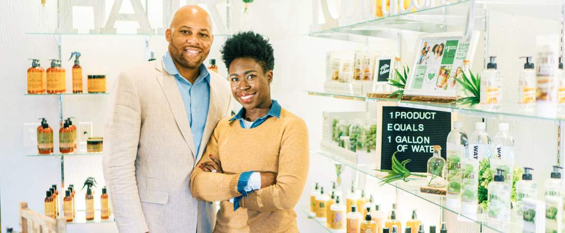 Two business owners standing in front of shelves full of products